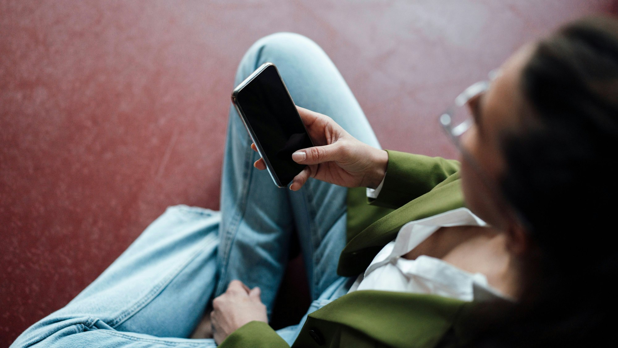 Eine junge Frau hält ein Smartphone in der Hand.