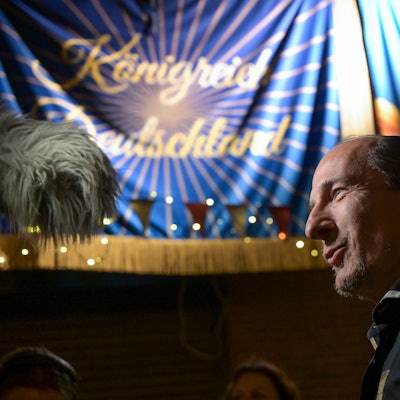 Peter Fitzek, selbsternannter Oberster Souverän und „König von Deutschland“, im Seitenporträt. Im Hintergrund sieht man ein Banner mit der Aufschrift „Königreich Deutschland“.