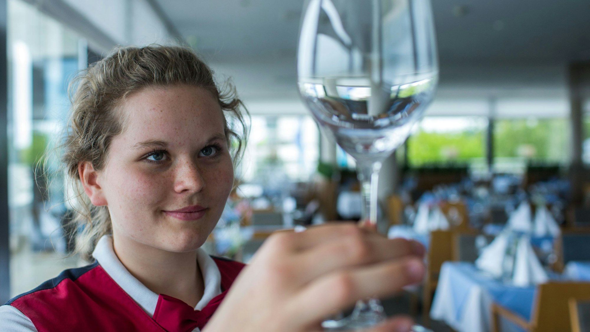 Alles muss blitzen: Eine Jugendliche kontrolliert in einem Restaurant ein frisch geputztes Weinglas. Auch Oberbergs Gastronomie wartet mit einem vielseitigen Angebot an Ferienjobs auf.