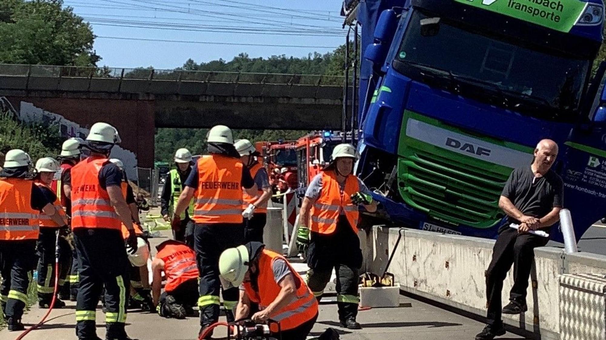Das Bild zeigt mehrere Einsatzkräfte der Feuerwehr an einem Lkw, der auf einen Betonschrammwand gefahren ist.