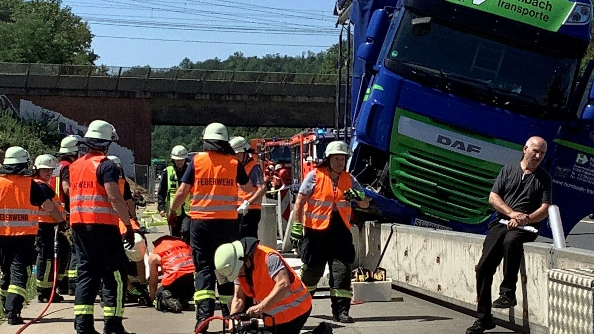 Das Bild zeigt mehrere Einsatzkräfte der Feuerwehr an einem Lkw, der auf einen Betonschrammwand gefahren ist.
