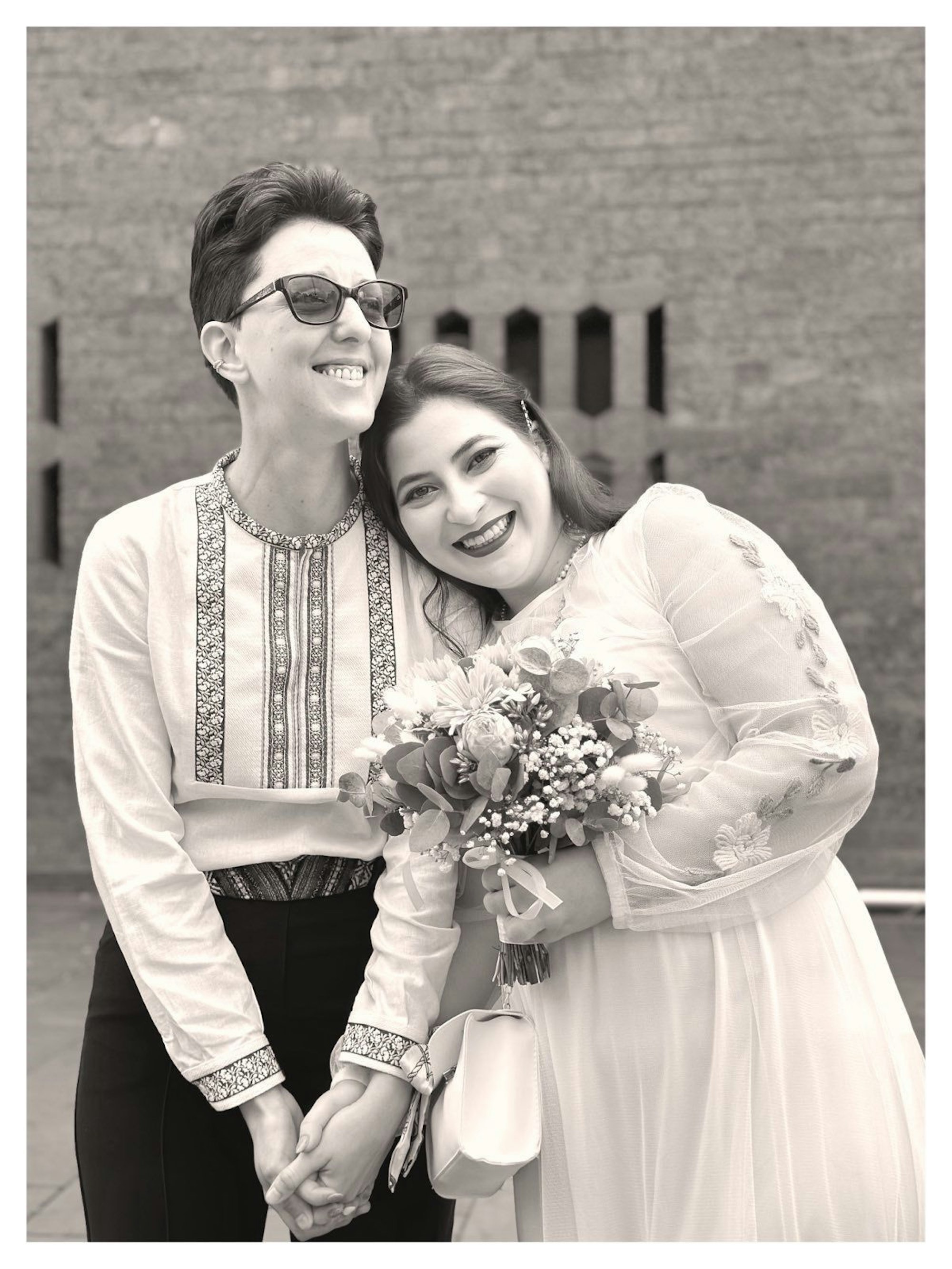 Adina Lupu (rechts) und Valeria Gavrilă bei ihrer Hochzeit in Köln. Sie lachen beide. Gavrilă lehnt sich an Lupu.