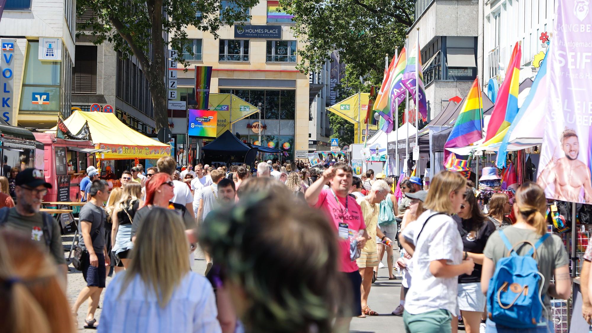 Eine große Menschenmenge läuft am Heumarkt. Am Rand sind bunte Flaggen zu sehen.