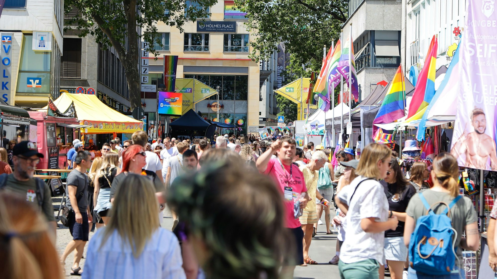 Eine große Menschenmenge läuft am Heumarkt. Am Rand sind bunte Flaggen zu sehen.