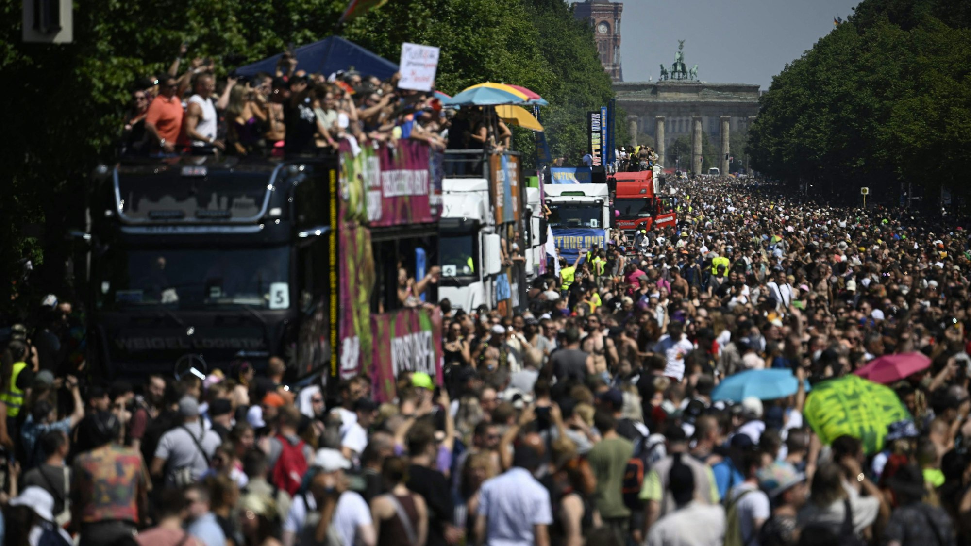 TOPSHOT - Participants pass the capital's landmark Brandenburg Gate as they celebrate during the "Rave the Planet" techno music parade on July 8, 2023 in Berlin. (Photo by Tobias SCHWARZ / AFP)