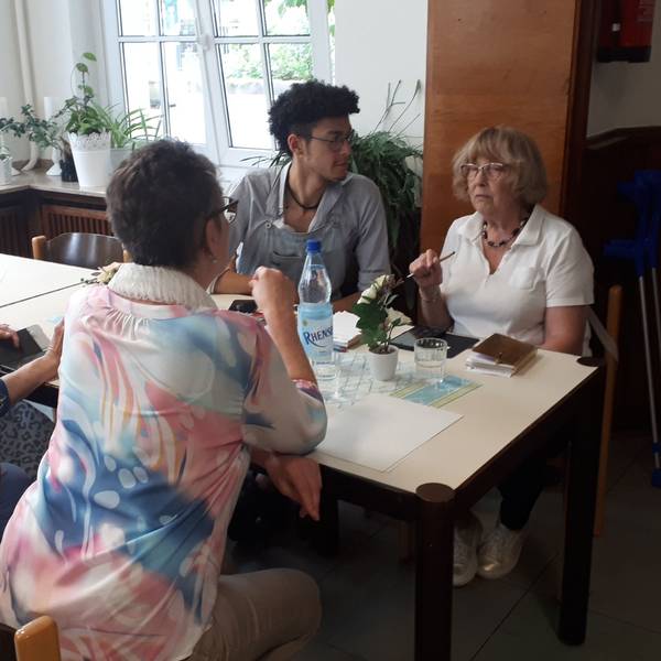 Ein junger Mann sitzt mit drei älteren Damen an einem Tisch.