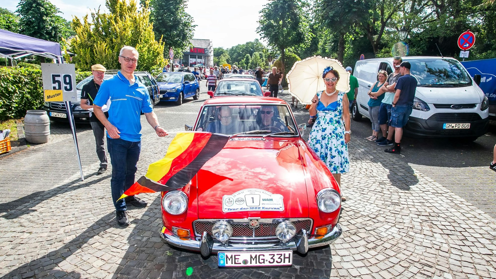 Lindlars Bürgermeister schwenkt die Startflagge bei der Abfahrt zur ADAC-Oldtimer-Rallye.