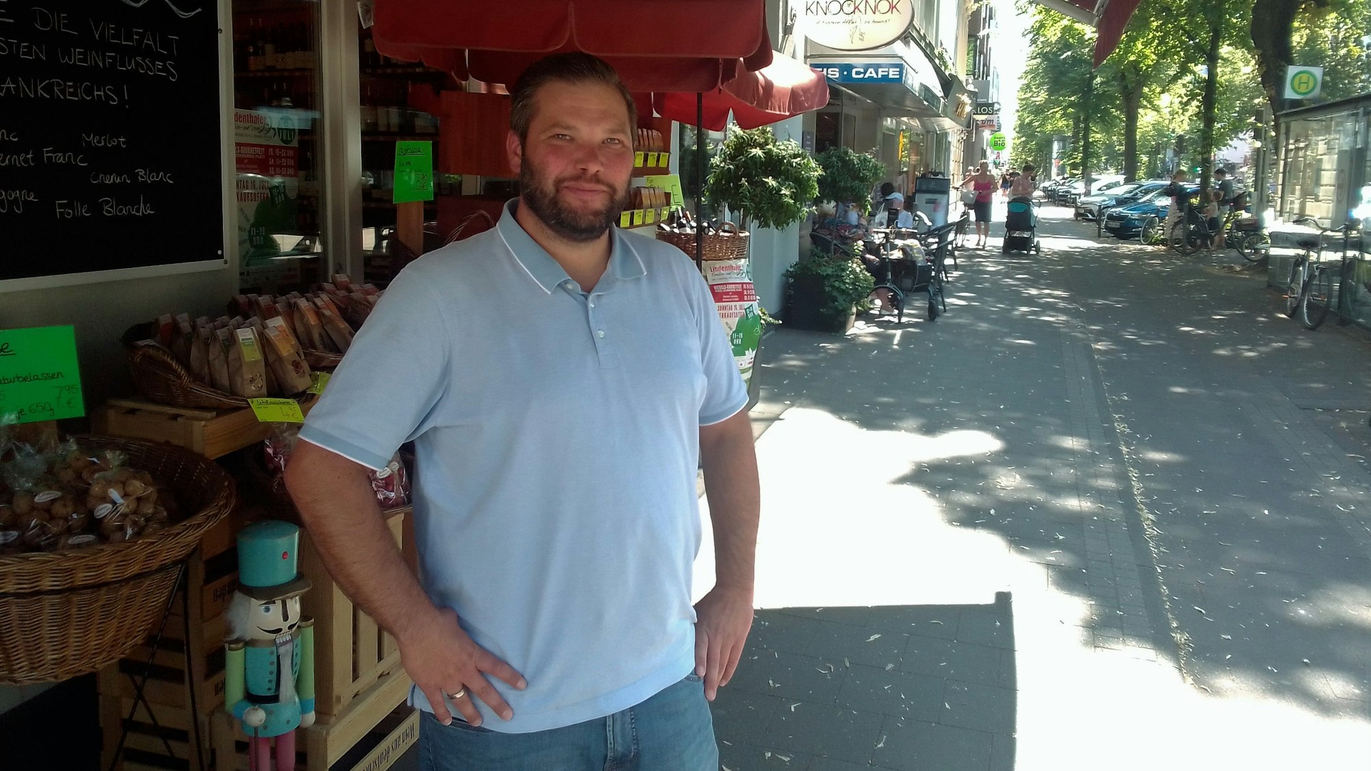 Ein Mann mit Bart steht vor seinem Geschäft.