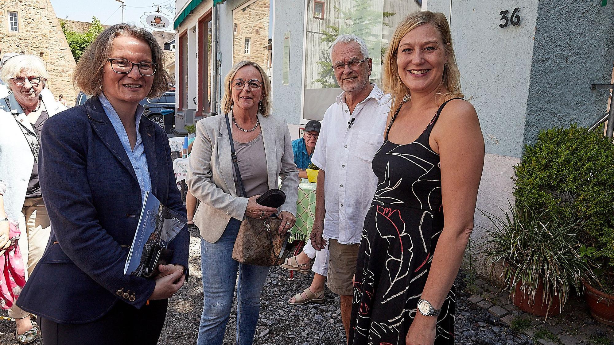 Ministerin Ina Scharrenbach (l.) und Bürgermeisterin Sabine Preiser-Marian (2.v.l.) sprechen mit Marcel Hayen und Melanie Dederichs, deren Geschäfte in Bad Münstereifel bei der Flutkatastrophe 2021 zerstört worden waren.