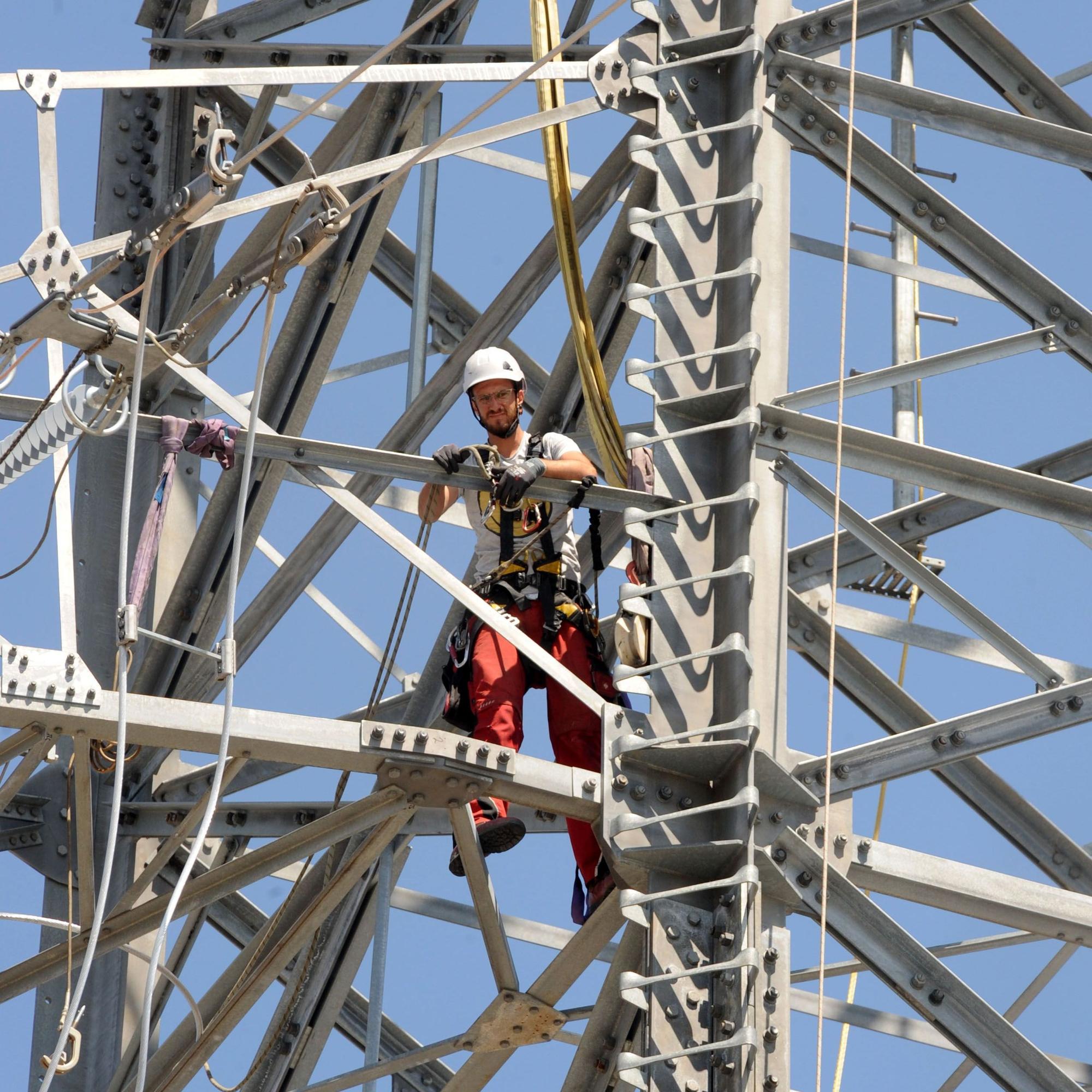 Das Bild zeigt einen Monteur auf einem Strommast.