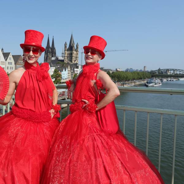 Zwei in Rot gekleidete Teilnehmende an der CSD-Parade stehen auf der Deutzer Brücke