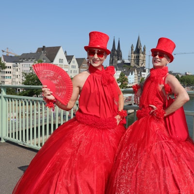 Zwei in Rot gekleidete Teilnehmende an der CSD-Parade stehen auf der Deutzer Brücke