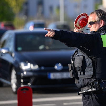 Ein Polizist winkt Autofahrer zu einer Kontrolle raus.