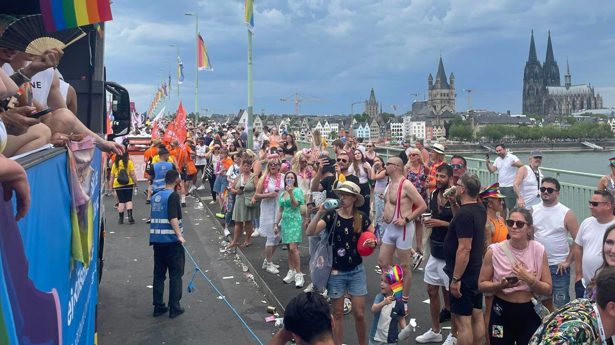 Dicht gedrängt stehen Menschen auf der Deutzer Brücke und schauen die vorbeiziehenden Wagen der CSD-Parade in Köln im Juli 2023 an.