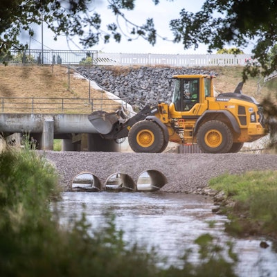 Mit einem gelben Radlader wird am Hochwasserrückhaltebecken bei Horchheim gearbeitet. Das Foto ist durch eine Böschung hindurch aufgenommen worden.