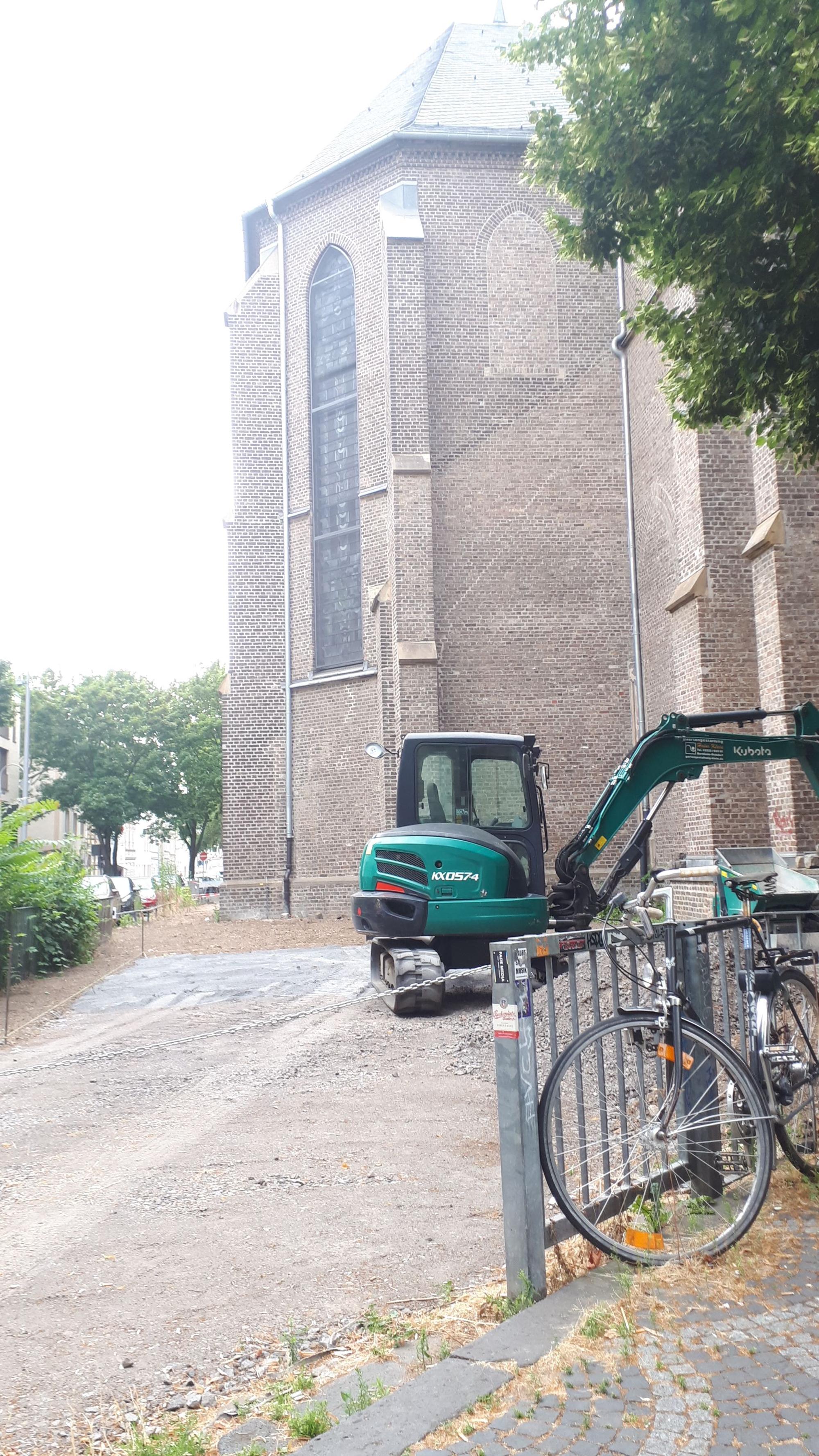 Vor der Kirche steht ein Bagger auf einer abgesperrten Baustelle.