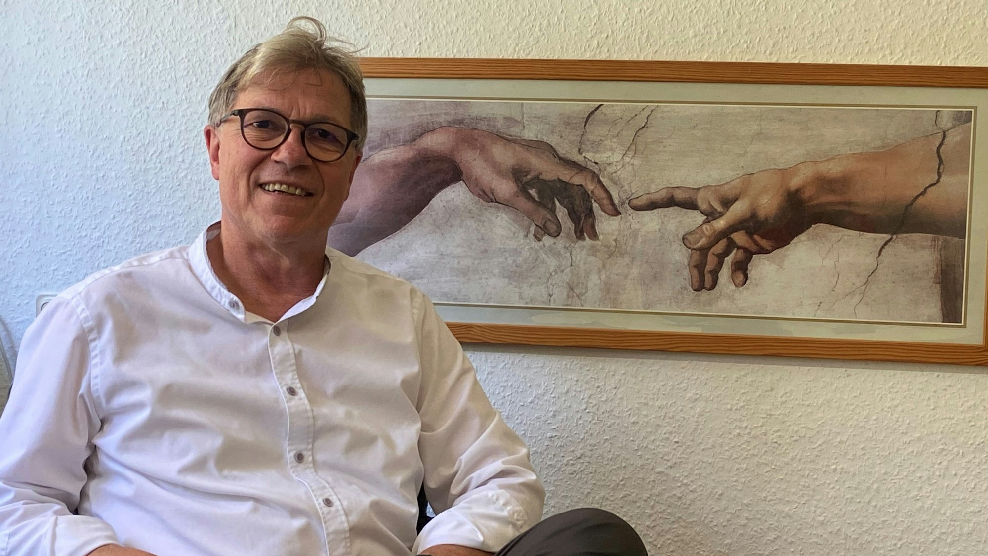 Ein Mann mit Brille und blondem Haar schaut lachend in die Kamera.