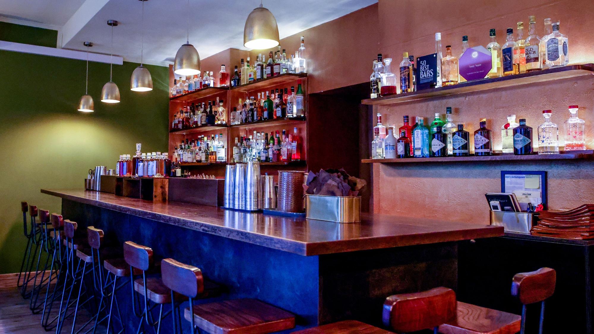 mit Holz verkleidete Bar, an der Wand dahinter Regale mit Flaschen