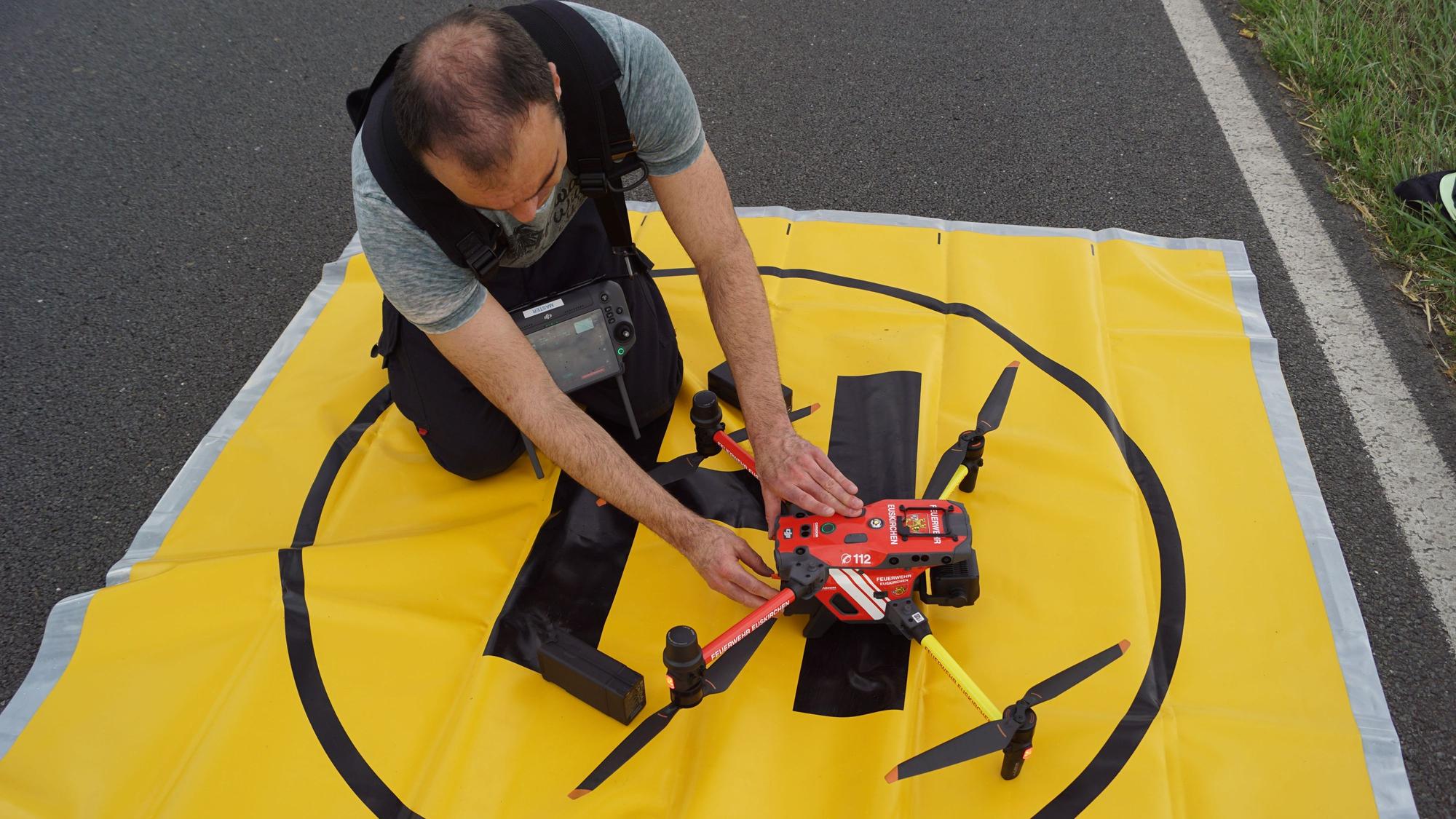 Der Pilot der Feuerwehr macht die Drohne auf ihrem Startplatz, der durch eine gelbe Folie markiert ist, startklar.