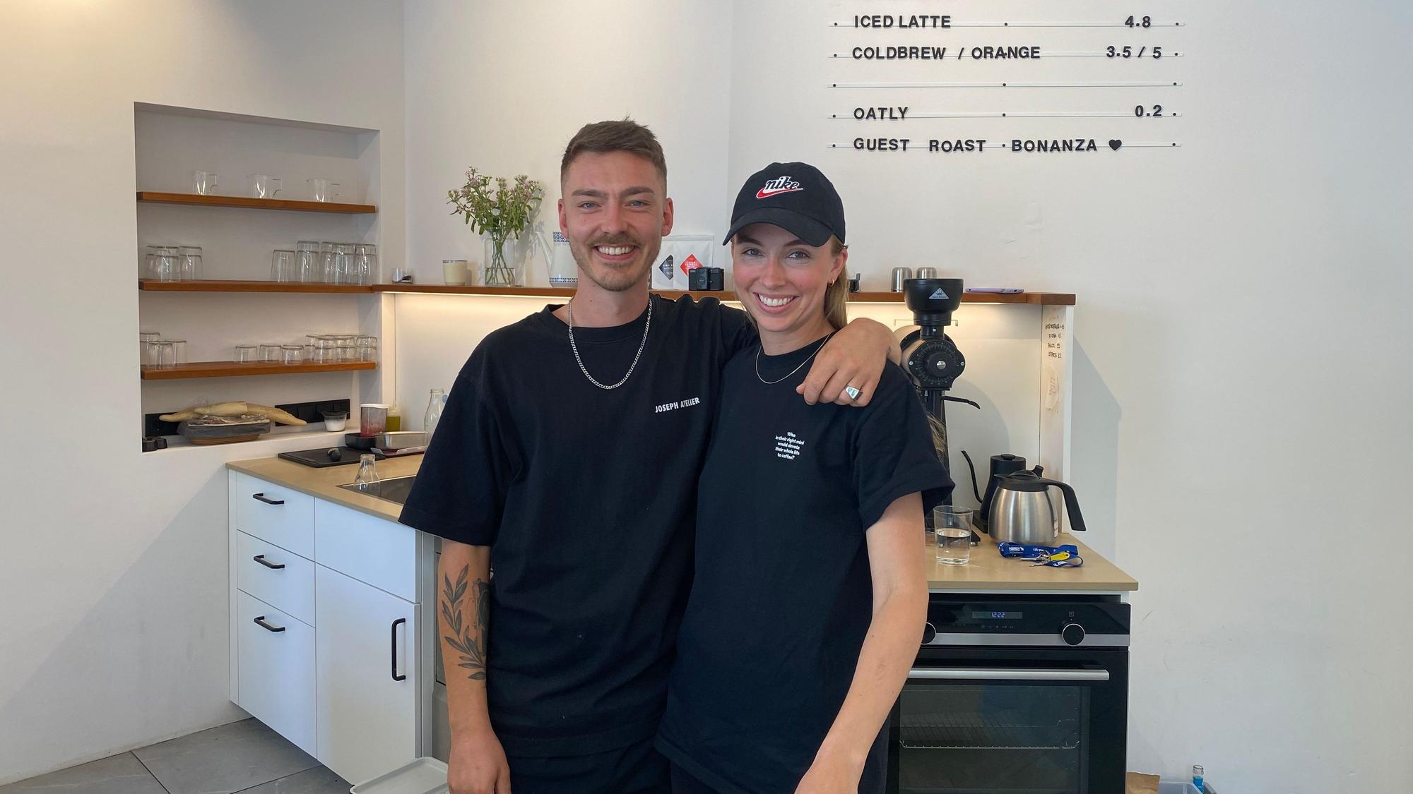 Auf dem Bild sieht man einen Mann und eine Frau, die hinter der Theke eines Cafés stehen.