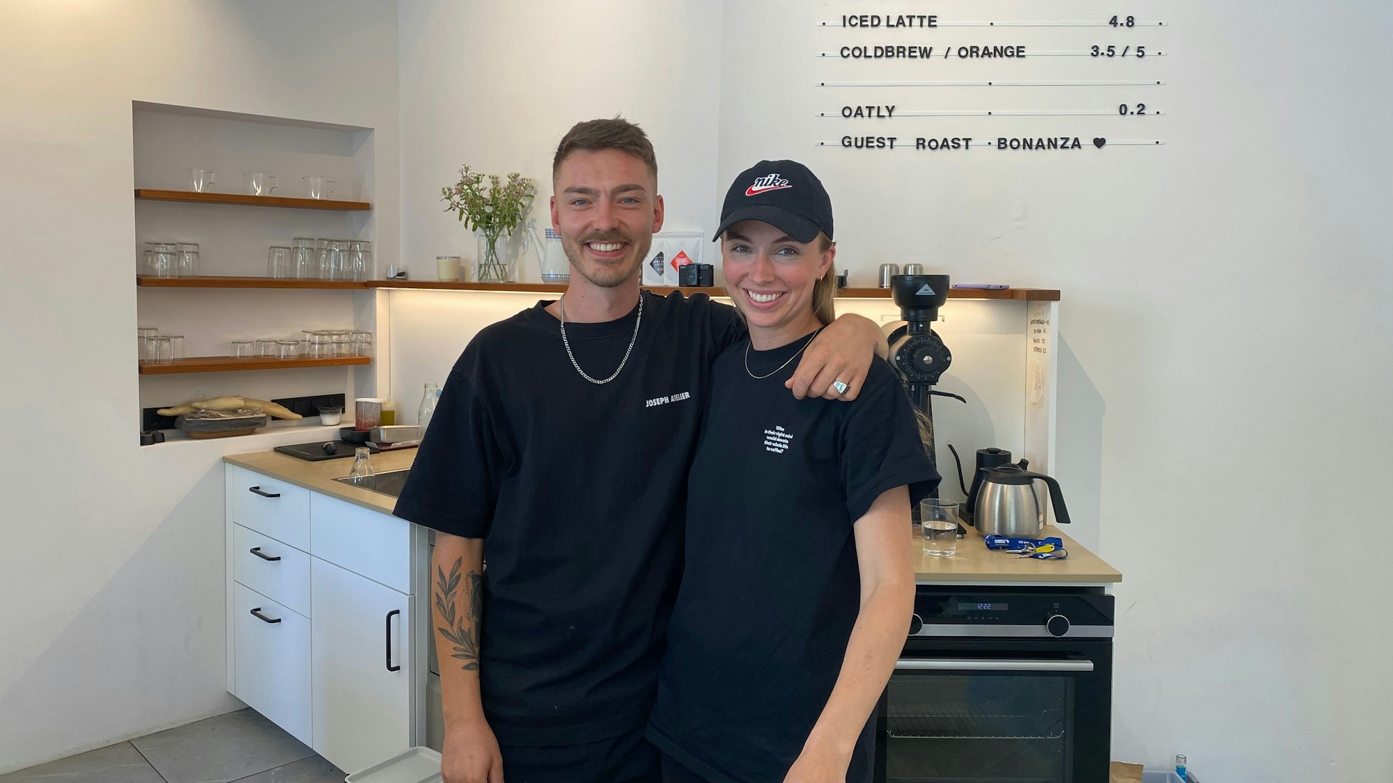 Auf dem Bild sieht man einen Mann und eine Frau, die hinter der Theke eines Cafés stehen.