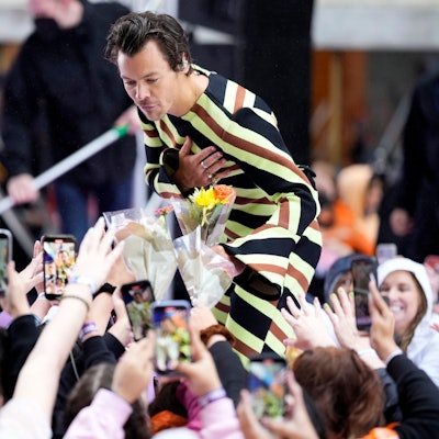 Harry Styles bei einem Auftritt in New York. Er nimmt Blumen entgegen.