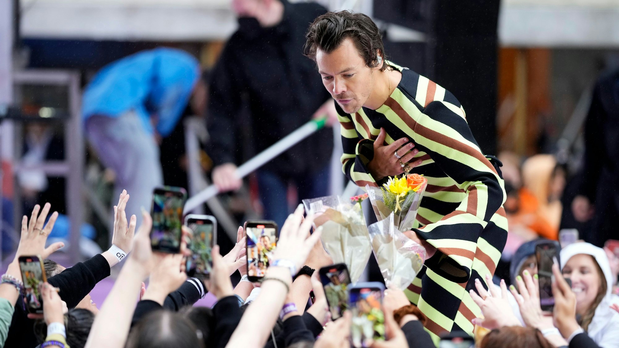 Harry Styles bei einem Auftritt in New York. Er nimmt Blumen entgegen.