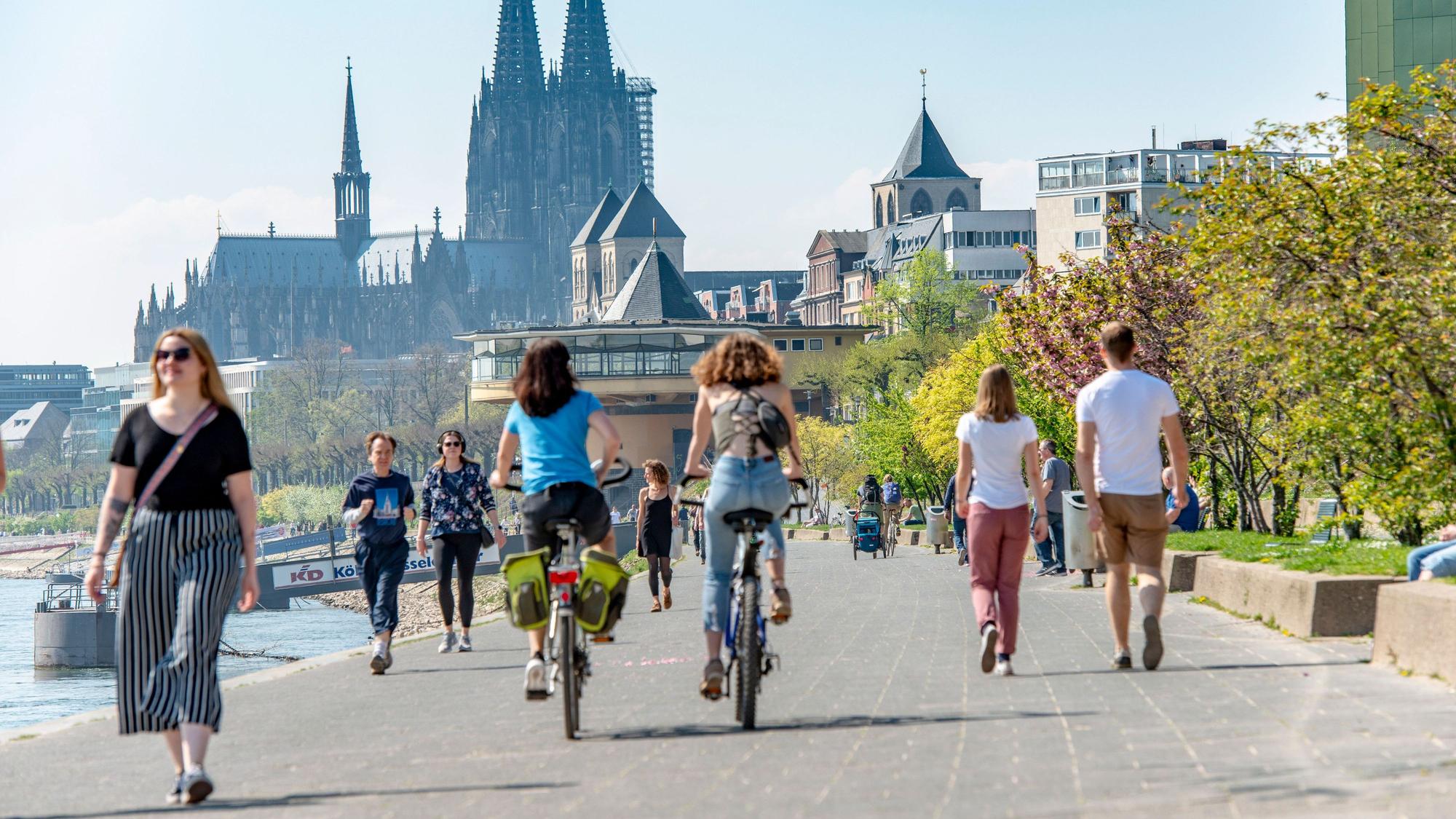 Mehrere Fußgängerinnen und Fußgänger teilen sich das schmale Konrad-Adenauer-Ufer in Köln, im Hintergrund ist die Bastei zu sehen.