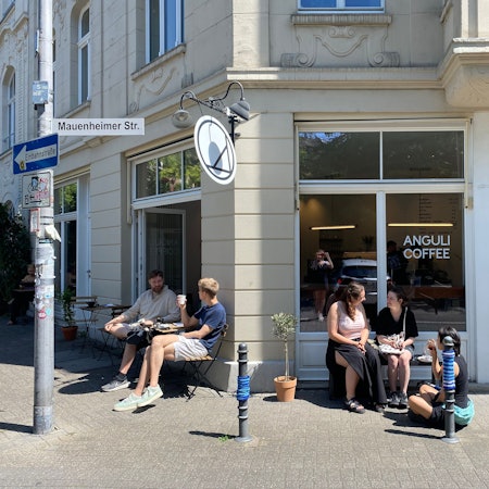 Auf dem Bild sieht man das neue Café „Anguli Coffee“ in Nippes von außen und sitzende Gäste.
