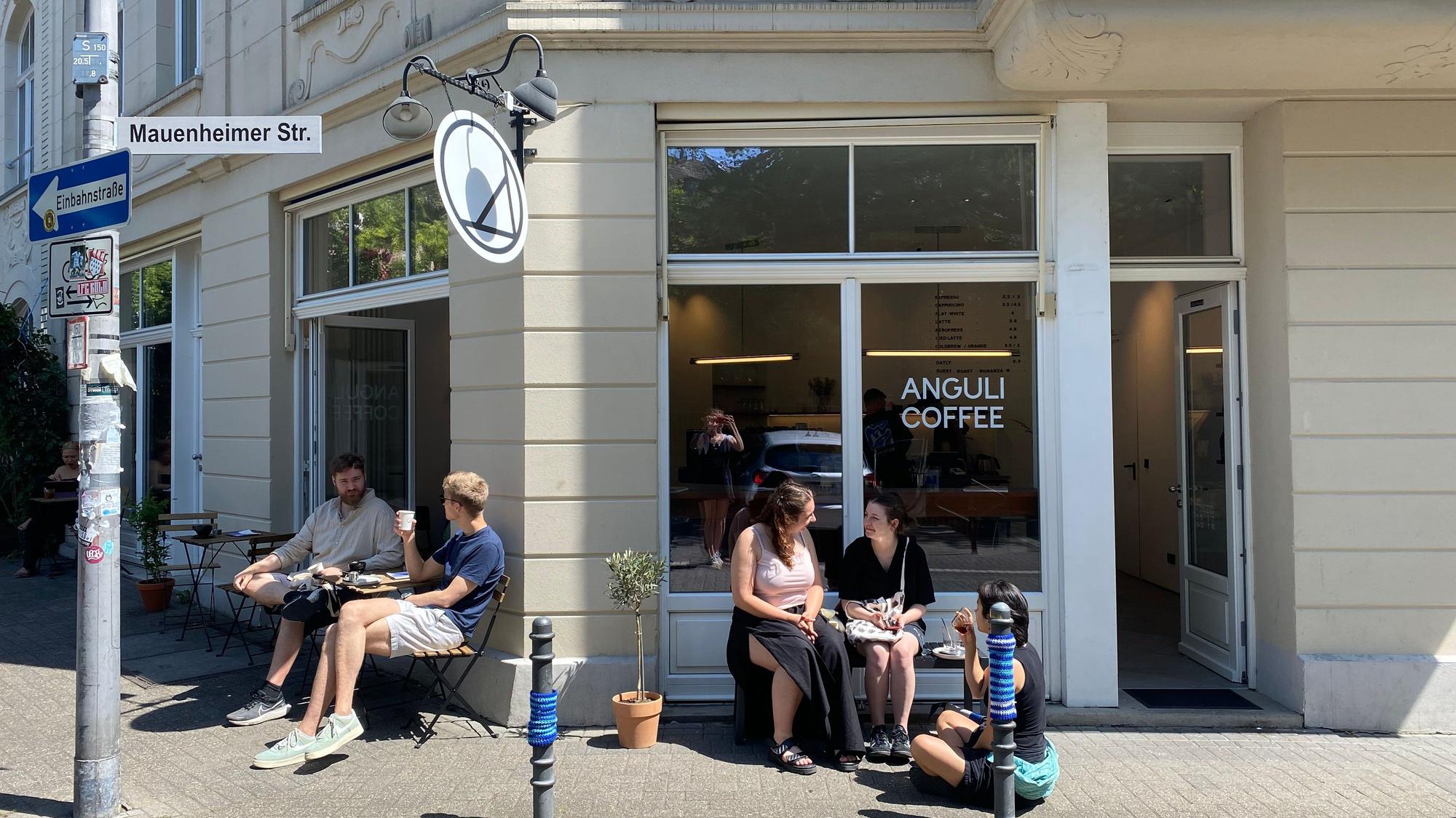 Auf dem Bild sieht man das neue Café „Anguli Coffee“ in Nippes von außen und sitzende Gäste.