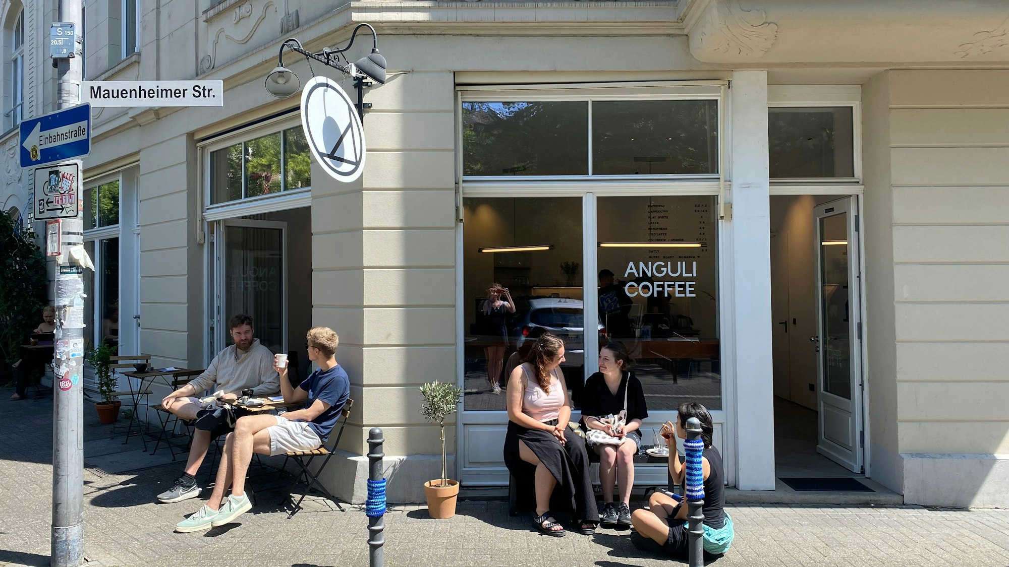 Auf dem Bild sieht man das neue Café „Anguli Coffee“ in Nippes von außen und sitzende Gäste.