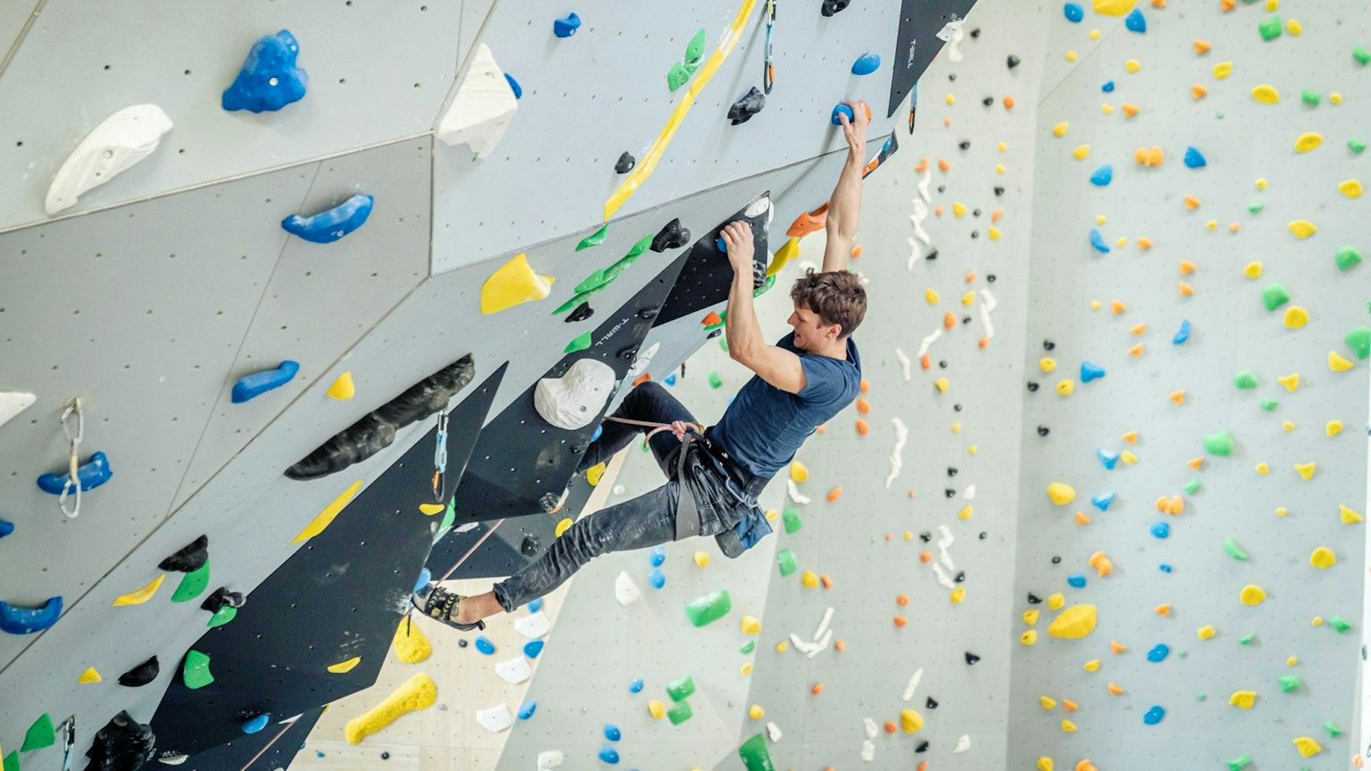 Ein Mann klettert an einer Kletterwand.