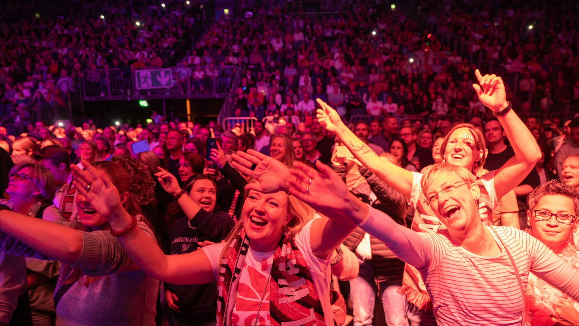 Menschen singen und winken in der Lanxess-Arena.