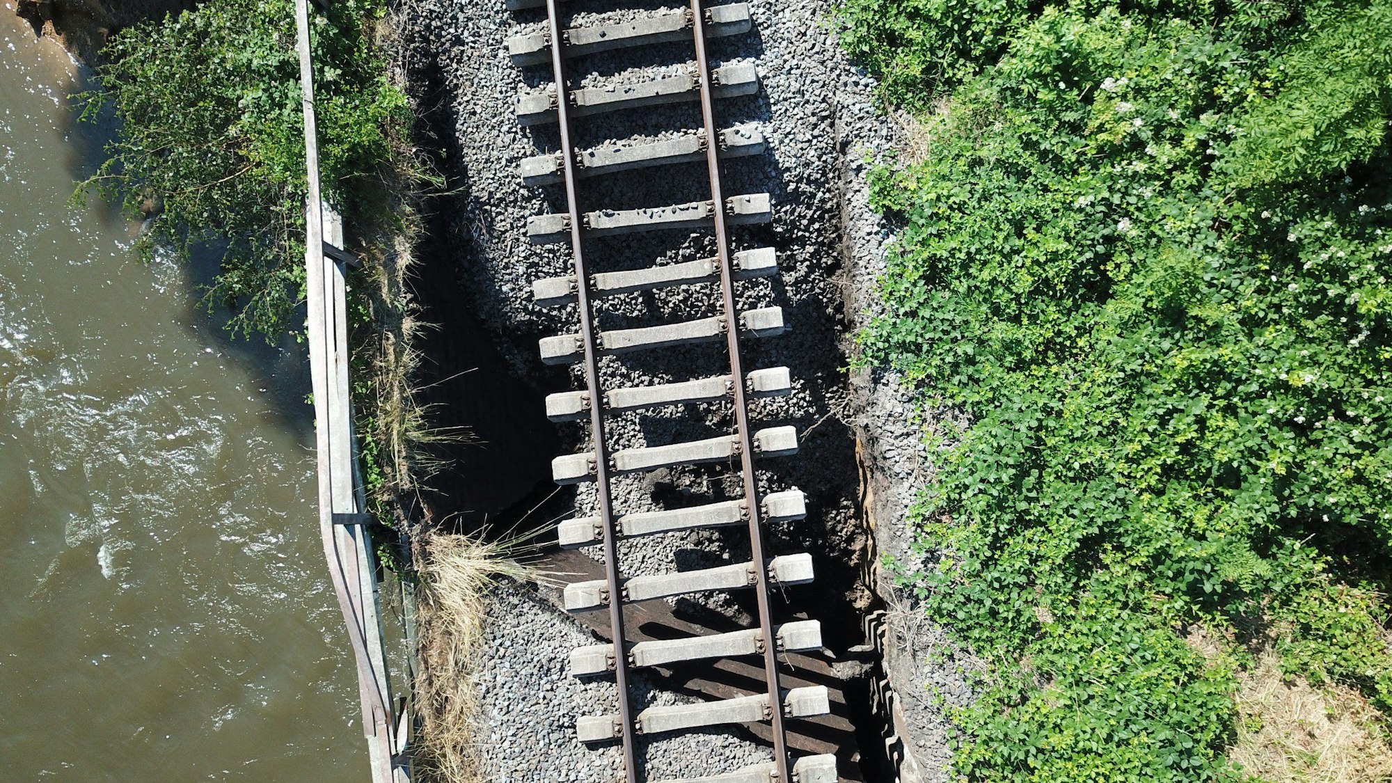 HANDOUT - 24.06.2023, Nordrhein-Westfalen, Dinslaken: Eine unterspülte Bahnbrücke an der Emscher ist nach heftigen Regenfällen abgesackt und droht einzustürzen. Am Unterlauf der Emscher hatte es nach den heftigen Unwettern bereits am Freitag große Probleme mit dem Hochwasserschutz gegeben. Der Deich sei auf Hunderten Metern erodiert, teilte das Umweltministerium mit. (zu dpa "Unwetter weicht Emscher-Deiche auf - Bahnbrücke abgesackt") Foto: ---/Stadt Dinslaken/dpa - ACHTUNG: Nur zur redaktionellen Verwendung im Zusammenhang mit der aktuellen Berichterstattung und nur mit vollständiger Nennung des vorstehenden Credits +++ dpa-Bildfunk +++