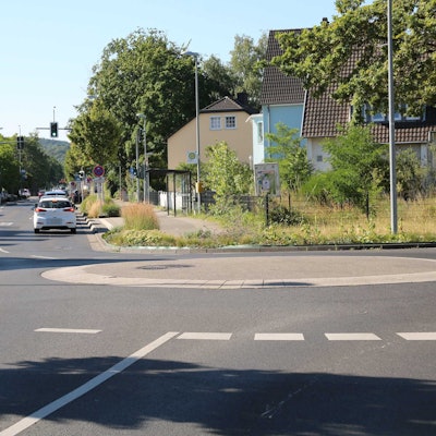 Autos fahren über die Linzer Straße. Im Vordergrund befindet sich der Mini-Kreisel am Floßweg.