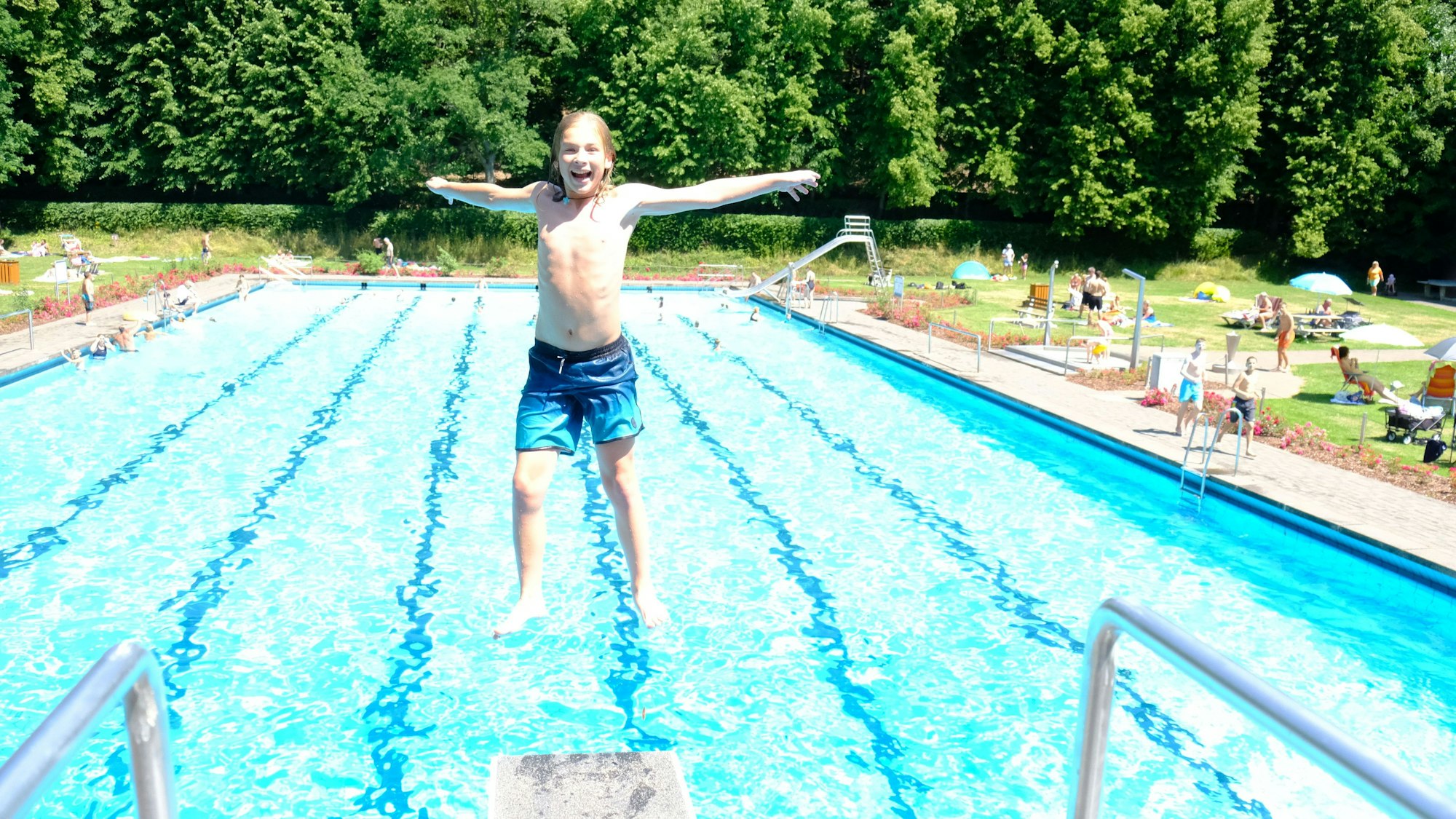 Ein Junge springt rückwärts vom Drei-Meter-Brett.