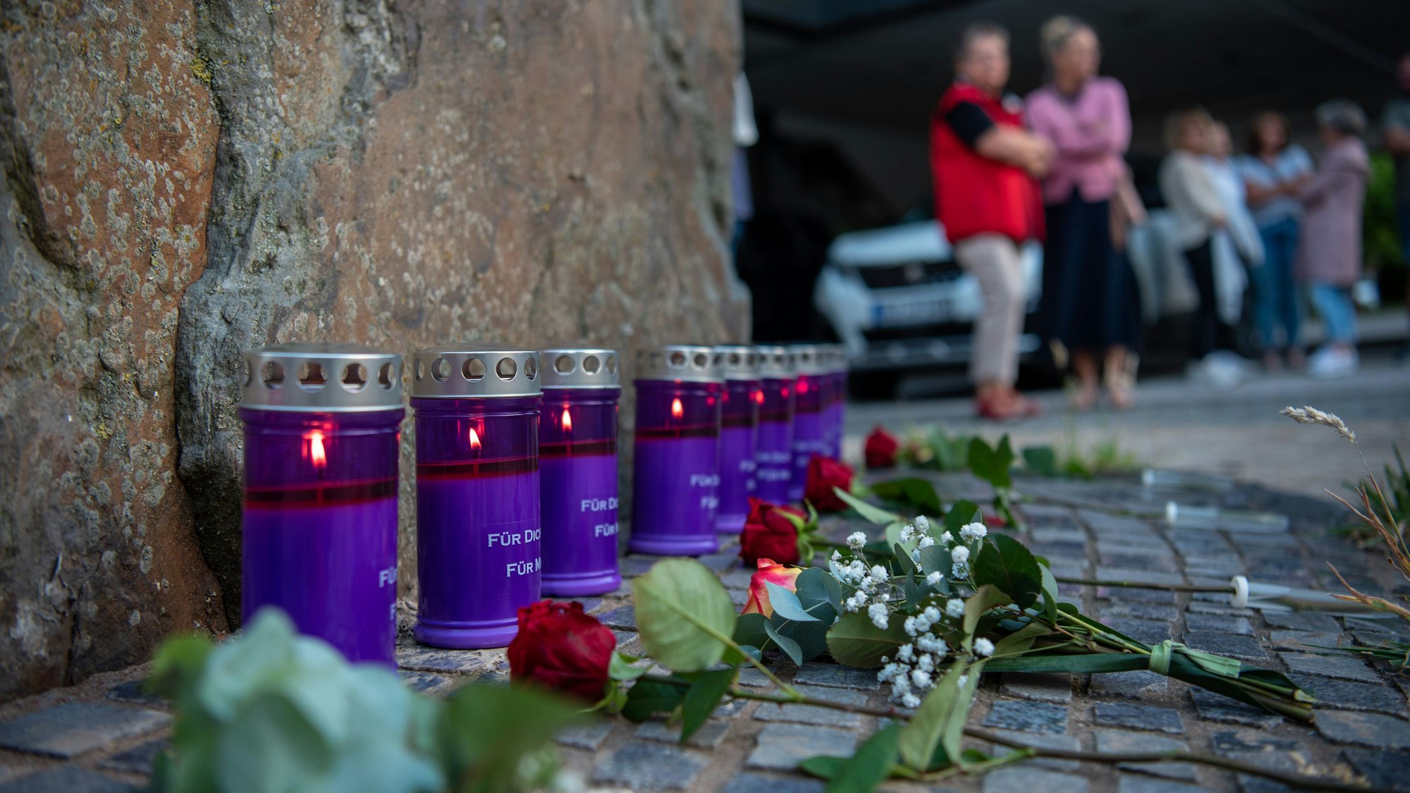 Einige Kerzen und Rosen sind vor einem Stein zu sehen. Mit ihnen wird der Menschen gedacht, die bei der Flutkatastrophe in der Stadt Schleiden gestorben sind.