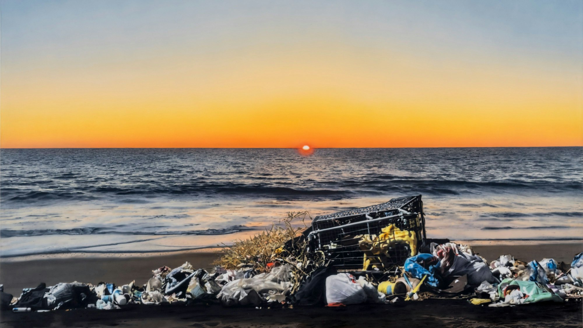 Ein Einkaufswagen und Müll liegen am Strand, im Hintergrund versinkt die Sonne am Meereshorizont.