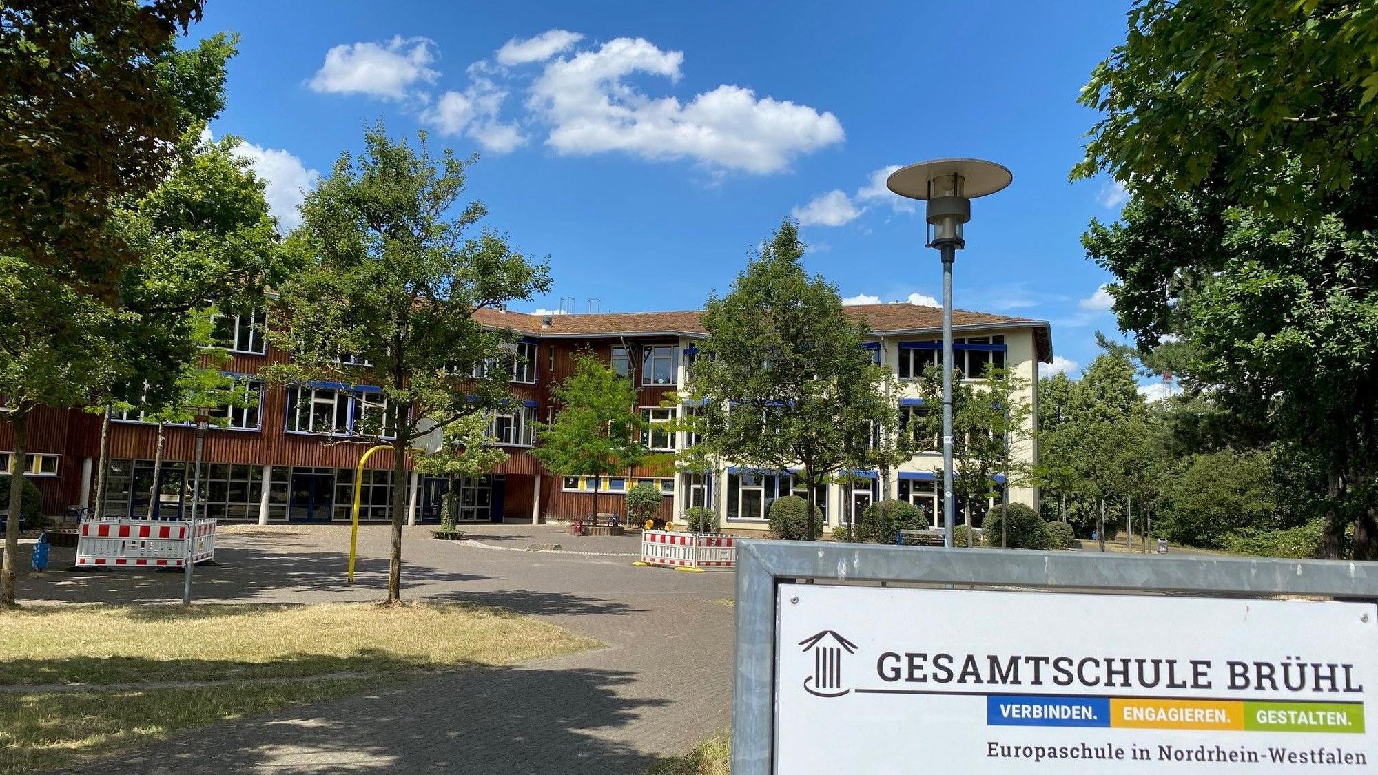 Das Foto zeigt die bestehende, von Bäumen umstandene Brühler Gesamtschule.