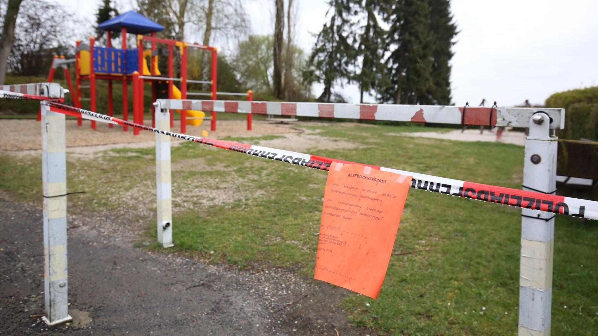 Ein Spielplatz ist mit rot-weißem Flatterband abgesperrt. Daran hängt ein roter Zettel.