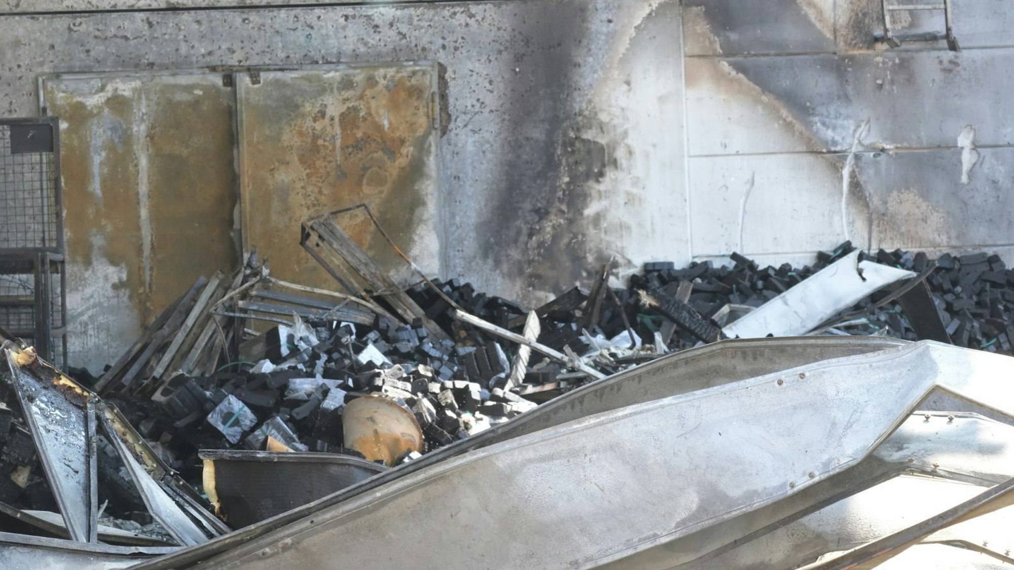 Nach dem Brand am Hagebaumarkt sieht man verkohlte Mauern und Trümmer, die auf dem Boden liegen.