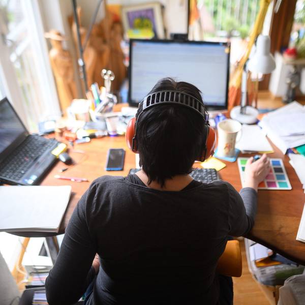 Eine Frau arbeitet mit Hörschutz im Homeoffice.