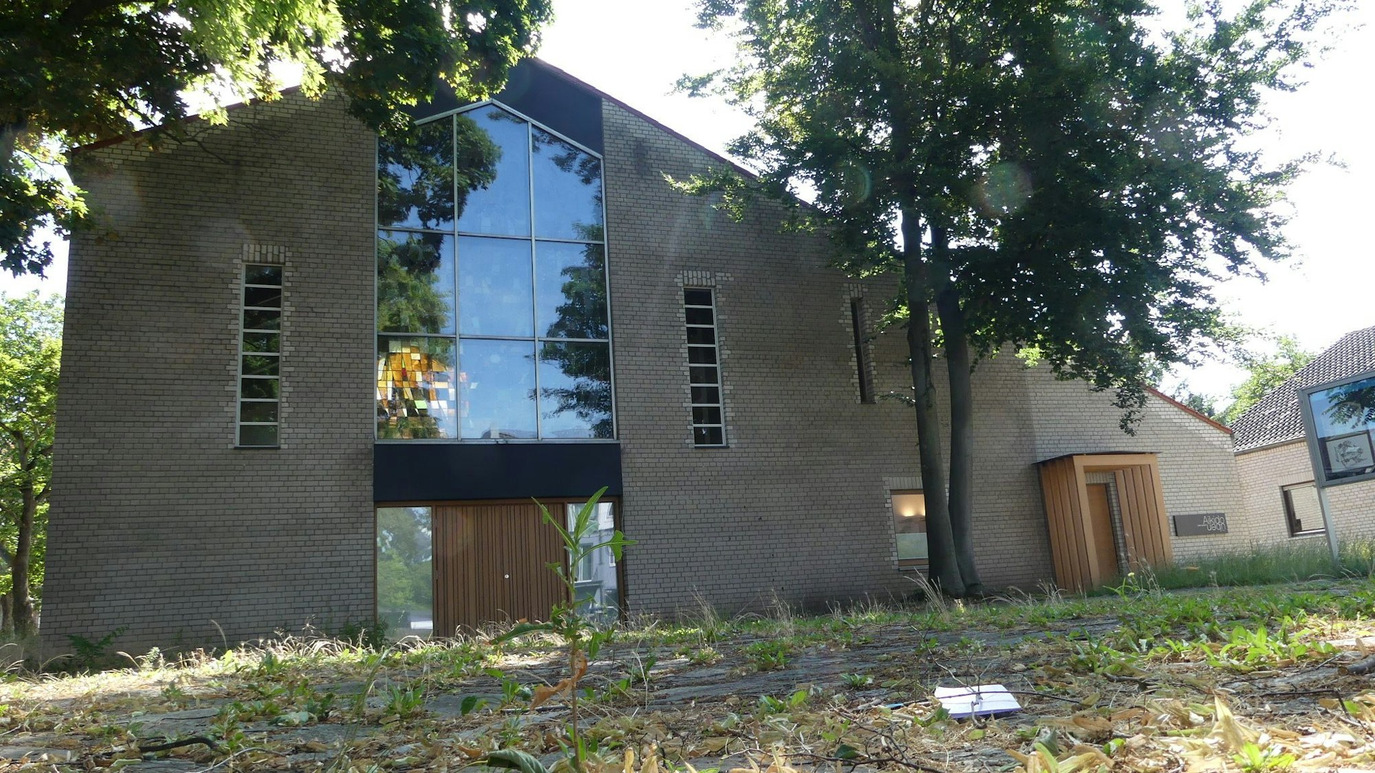Ein von Unkraut überwucherter Platz vor einem Kirchengebäude ist zu sehen.