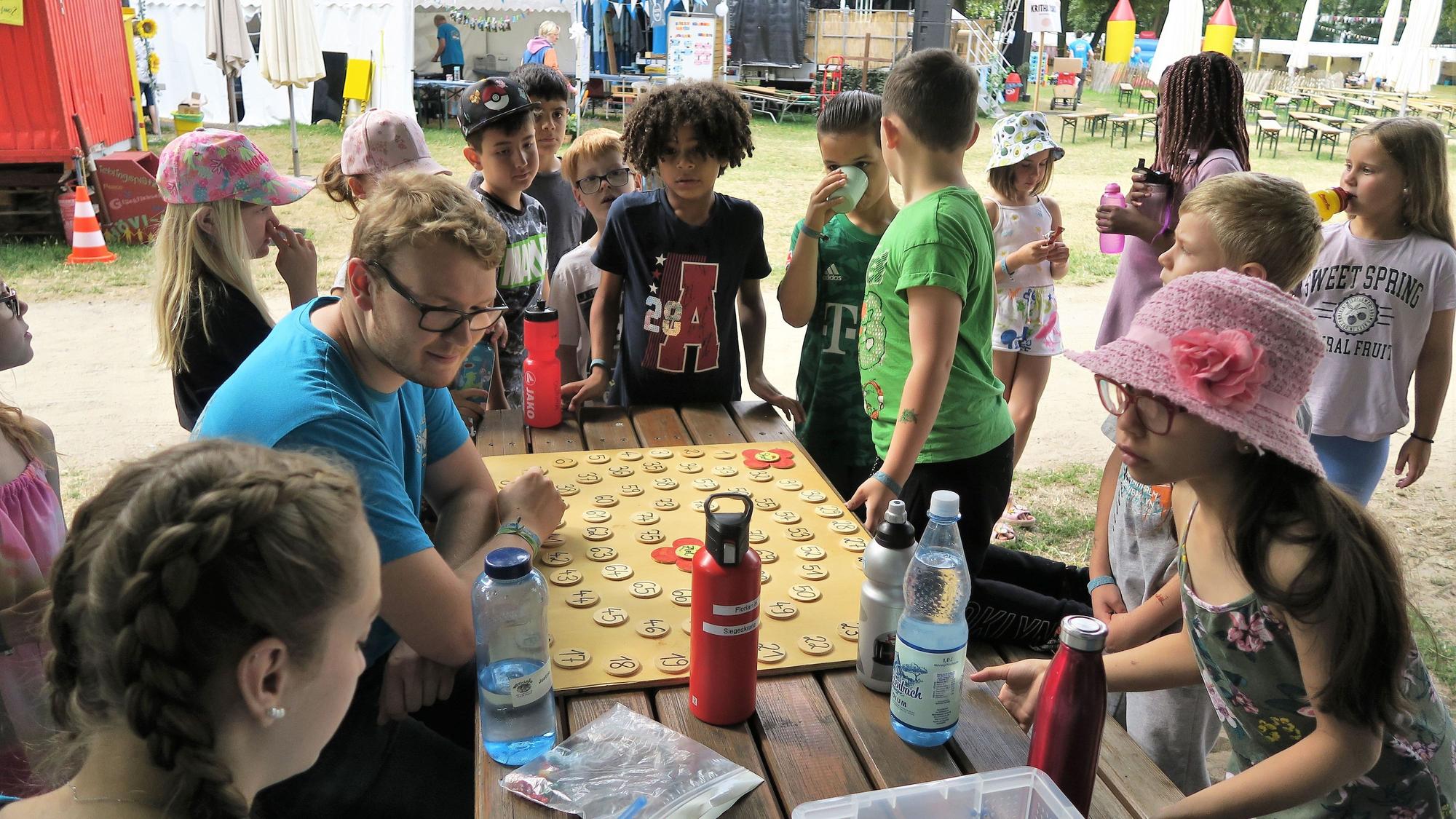 Kinder stehen um einen Tisch herum und spielen ein Spiel.