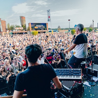 Zu sehen ist die Kölner Band Kasalla im Jahr 2022 auf einer Bühne beim Parookaville-Festival. Davor befindet sich eine Menschenmasse.