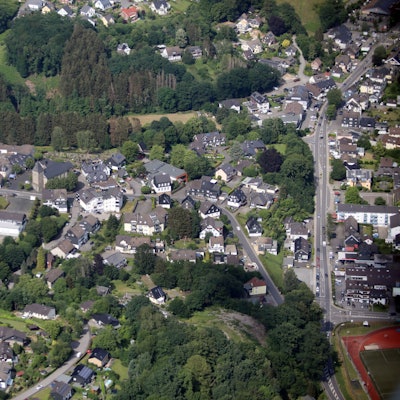 Luftbild von Kürten mit Oberdorf und Kirche, rechts der Sportplatz.