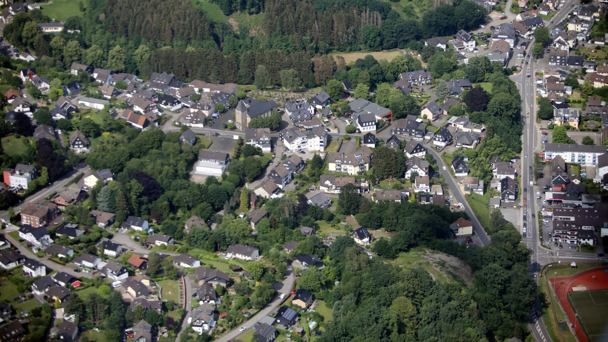 Luftbild von Kürten mit Oberdorf und Kirche, rechts der Sportplatz.