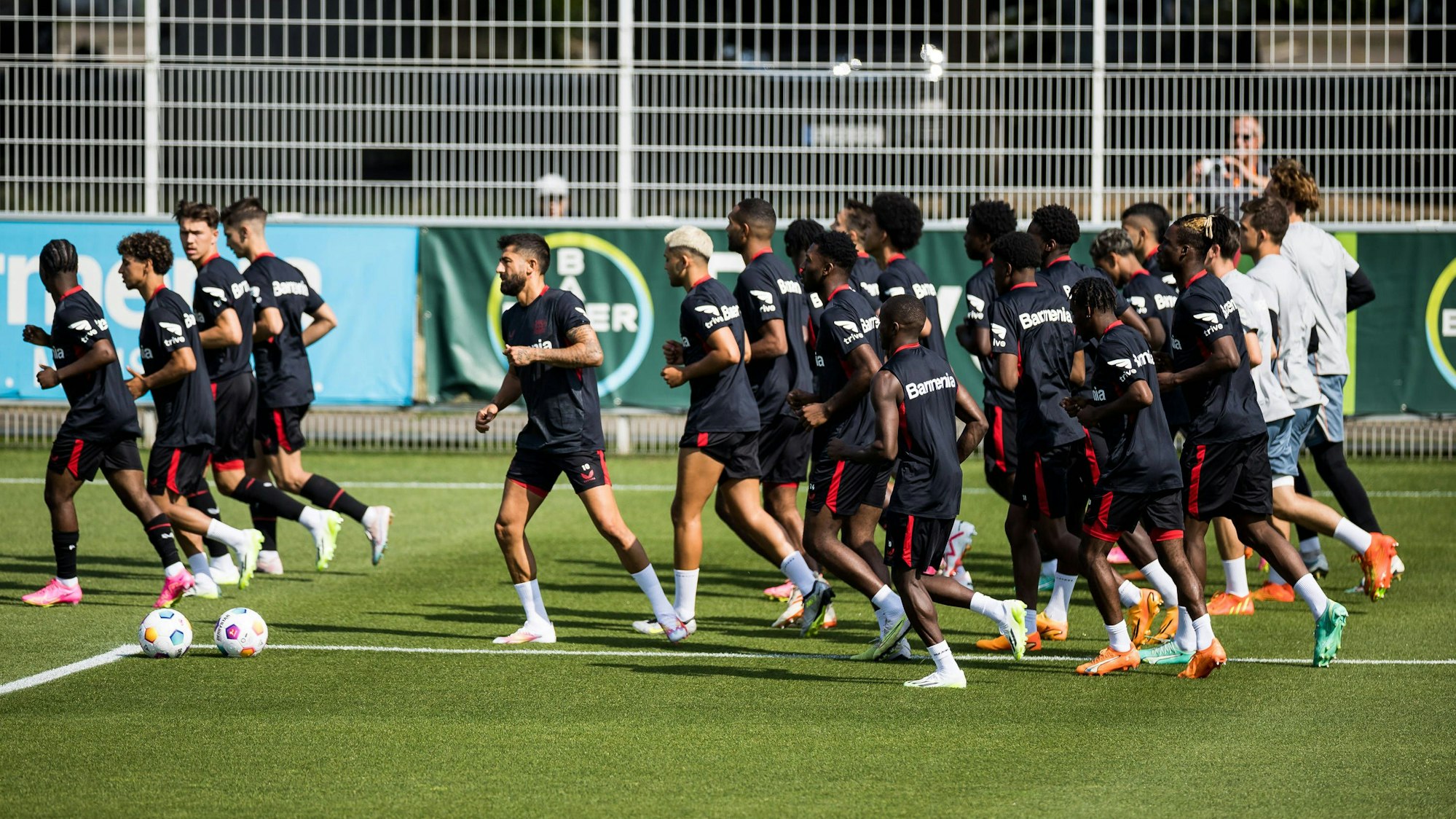 Fußball-Profis von Bayer Leverkusen laufen in der Gruppe über den Rasen.