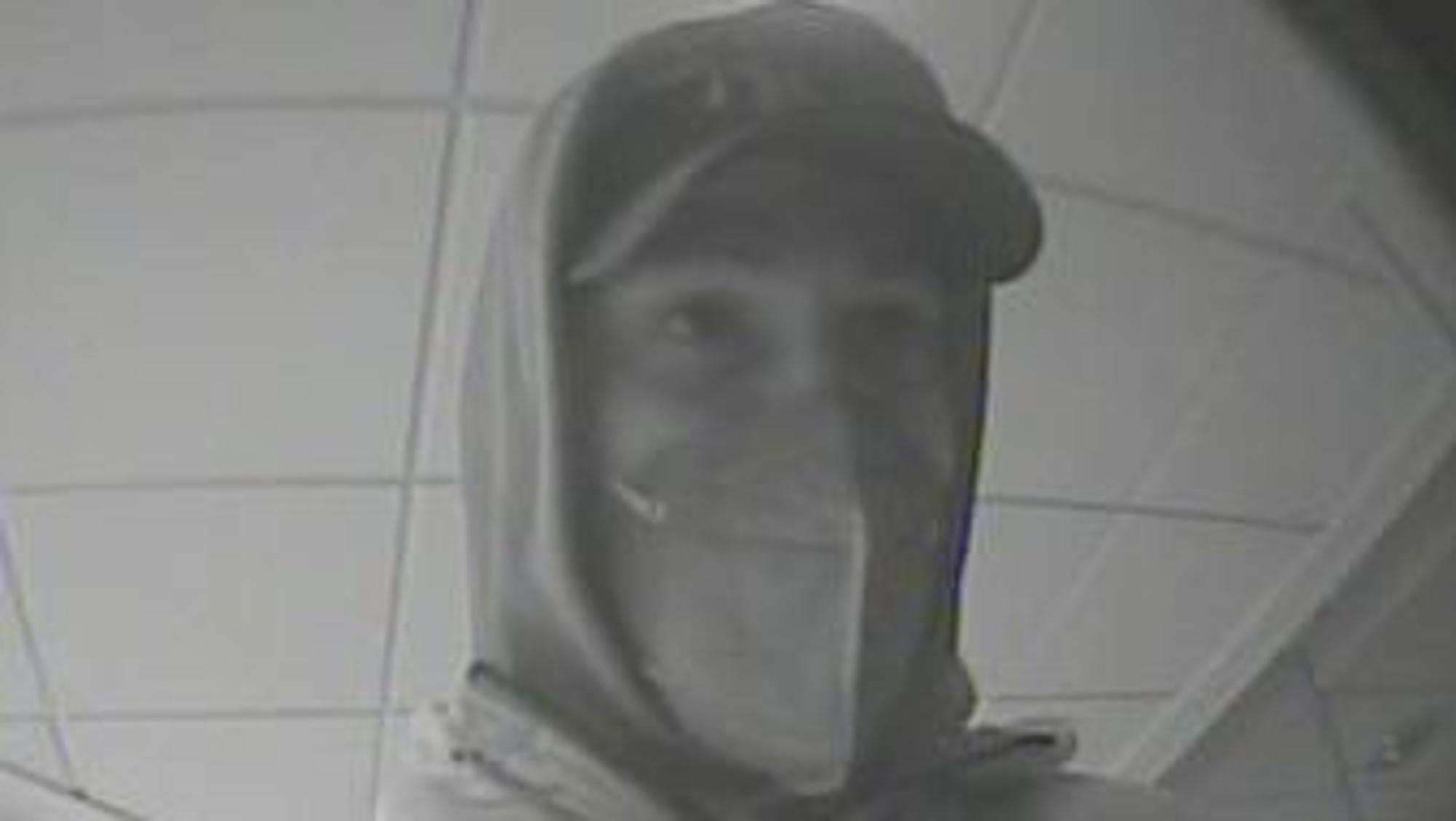 Das Bild zeigt einen Mann mit Kapuzenpulli und Basecap, der von der Überwachungskamera der Bank gefilmt wurde.