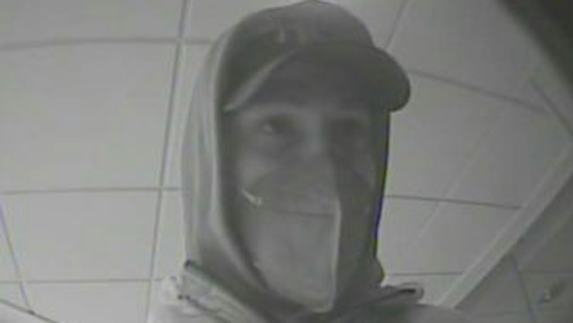 Das Bild zeigt einen Mann mit Kapuzenpulli und Basecap, der von der Überwachungskamera der Bank gefilmt wurde.
